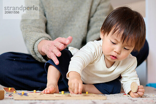 Asian kid playing with wooden toys on the floor