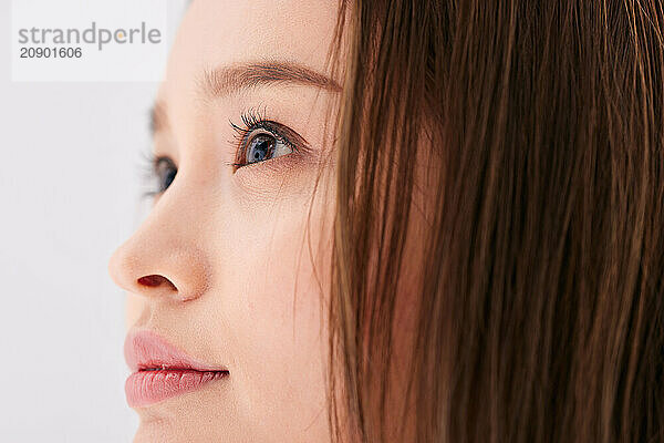 Asian Woman With Long Brown Hair Looking Off To The Side