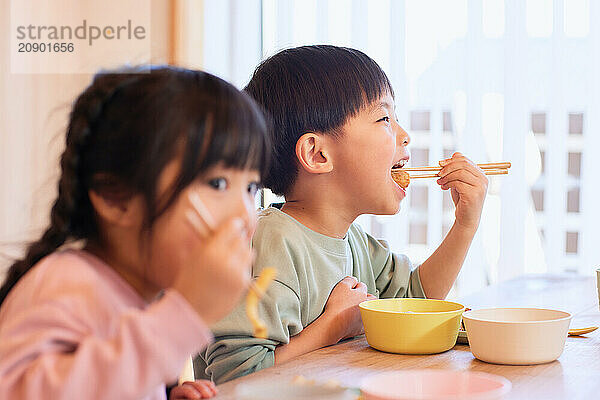 Happy Japanese kids eating in the dining room