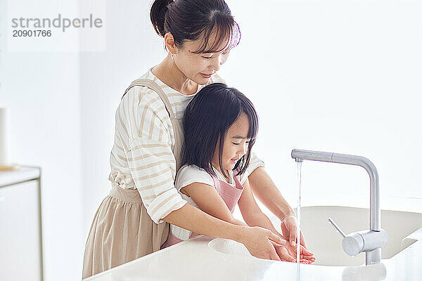 Asian woman and child washing their hands in a sink