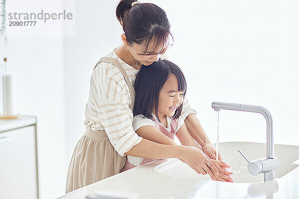 Asian woman and child washing their hands in a sink