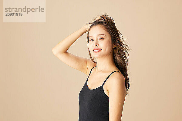 Beautiful Asian Woman In Black Tank Top Posing On Beige Background