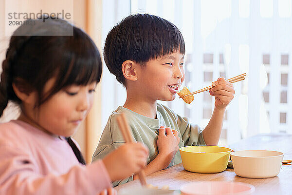 Happy Japanese kids eating in the dining room