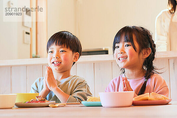 Happy Japanese kids eating in the dining room