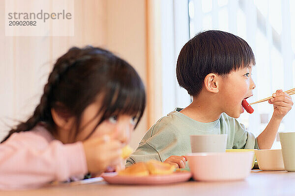 Happy Japanese kids eating in the dining room