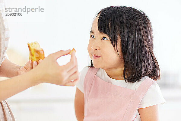 Young Asian girl is eating a piece of bread