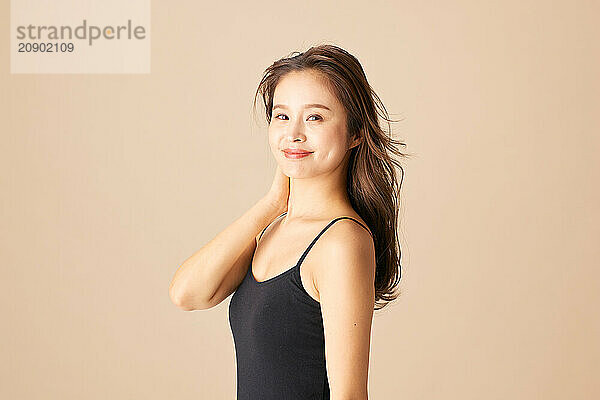 Beautiful Asian Woman In Black Tank Top Posing On Beige Background