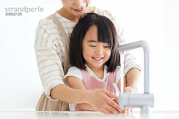 Asian woman and child washing their hands in a sink