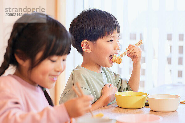 Happy Japanese kids eating in the dining room