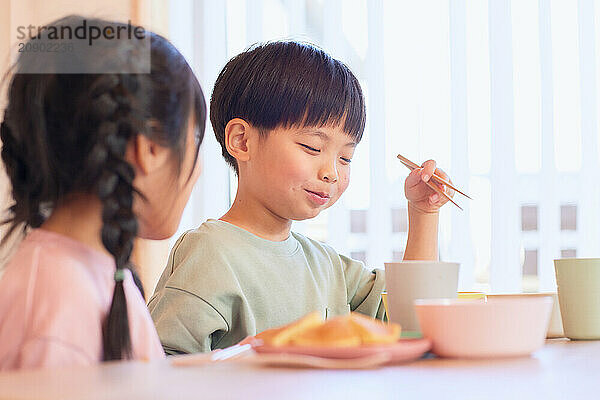 Happy Japanese kids eating in the dining room