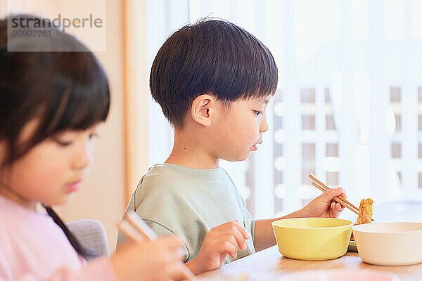 Happy Japanese kids eating in the dining room