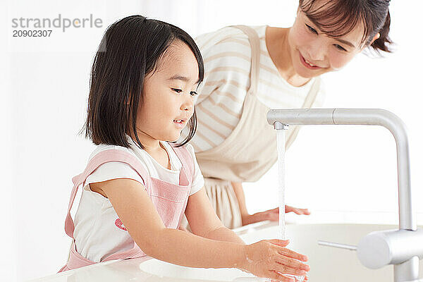 Asian woman and child washing their hands in a sink