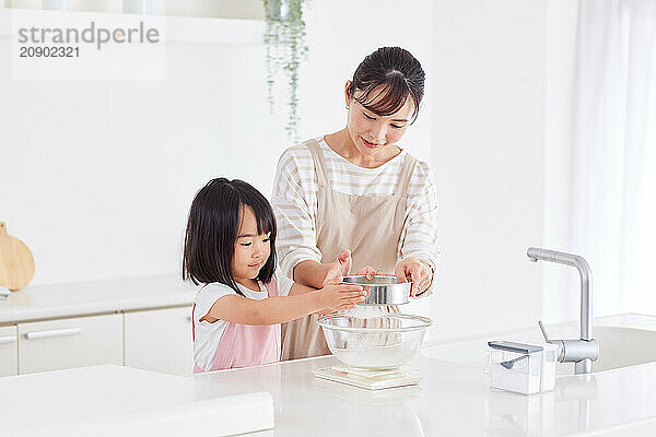 Asian woman and child in the kitchen with a bowl