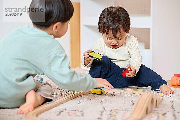 Asian children playing with toy trains on the floor