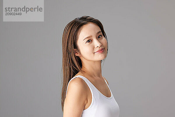 Asian Woman In A White Tank Top Posing For The Camera