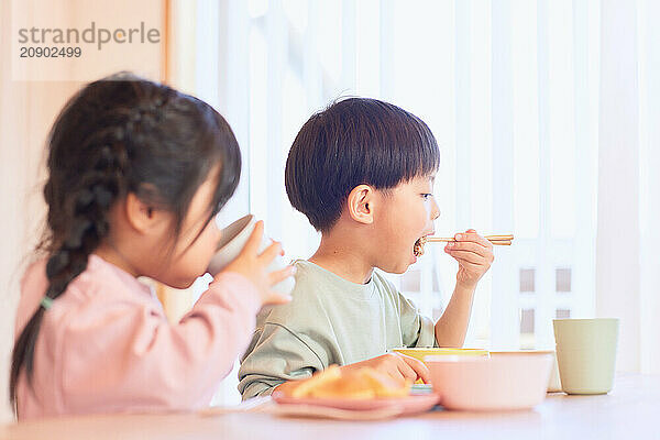 Happy Japanese kids eating in the dining room