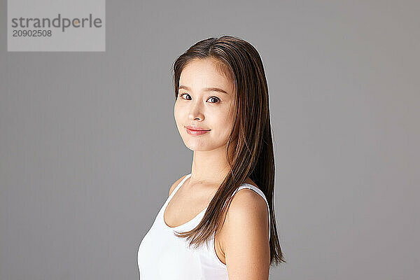 Asian Woman In A White Tank Top Posing For The Camera