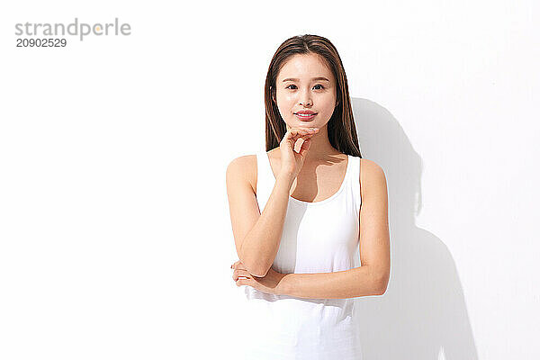 Asian Woman In A White Tank Top Posing For The Camera