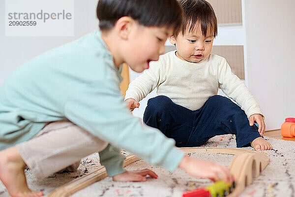 Asian children playing with wooden train tracks