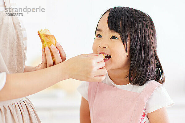 Young Asian girl is eating a piece of bread