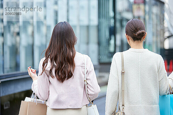 Two Women Walking Down The Street With Shopping Bags