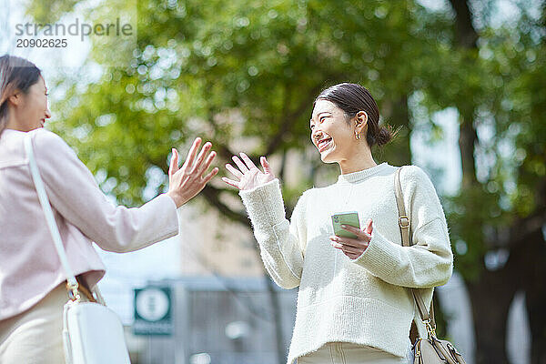 Two Women Talking And Giving A High Five