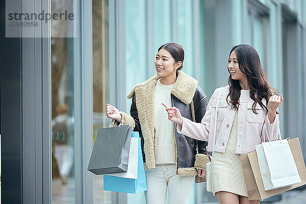 Two Women Walking Down The Street Holding Shopping Bags