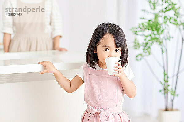 Young Asian girl drinking from a glass