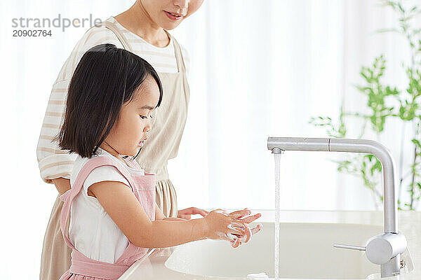 Asian woman and child washing their hands in a sink