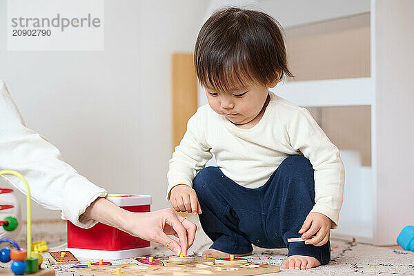 Asian woman and child playing with toys on a floor