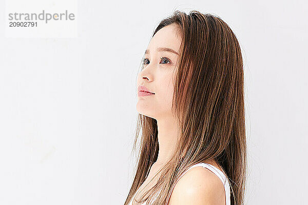 Asian Woman With Long Hair Standing In Front Of A White Wall