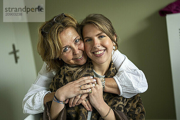 A joyful older woman embracing a younger woman with a fond expression indoors.