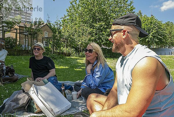 A group of friends enjoying a sunny picnic in the park with smiles and refreshments.