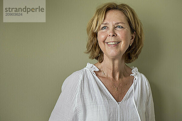 Smiling middle-aged woman in a white blouse against a plain background.