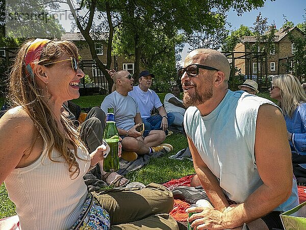 Friends enjoy a sunny picnic in the park  laughing and sharing a bottle of wine on a vibrant green lawn.