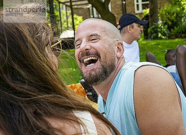 Laughing man enjoying a sunny day at an outdoor gathering with friends.