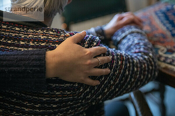 A close-up view of a person's hand gently resting on another person's shoulder  conveying a sense of comfort and support.