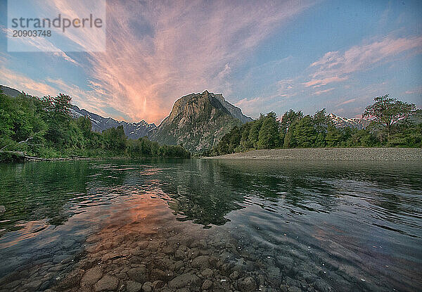 Sunset casts a warm glow over a tranquil river with a mountain backdrop  Golfo de Penos  Patagonia  Chile