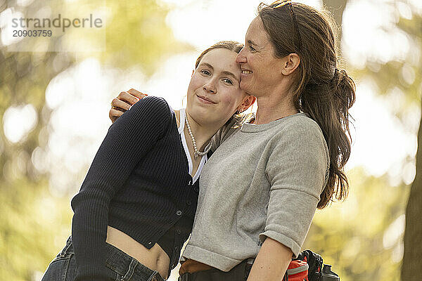 Mother and daughter sharing a tender moment with a loving embrace outdoors during golden hour.