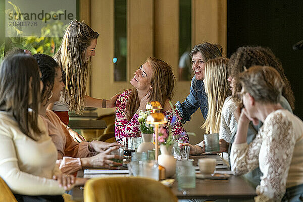 A group of women enjoying a conversation at a cozy cafe with warm lighting.