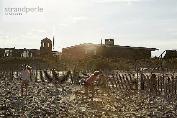 Group of friends playing at the beach during a beautiful sunset.