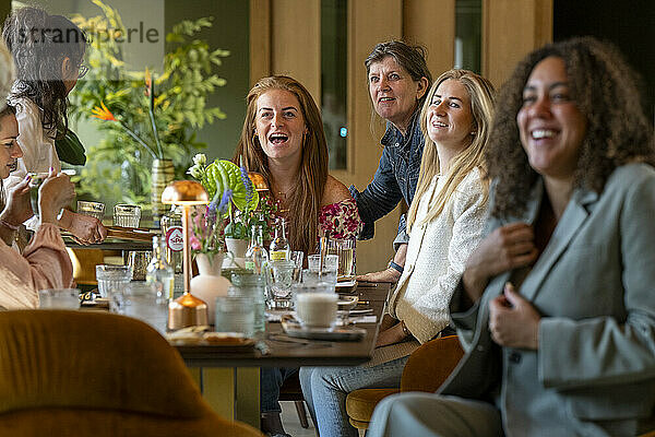 Group of women enjoying a laughter-filled meal together at a cozy restaurant.