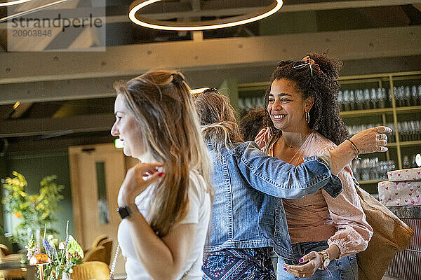 Joyful friends hugging and smiling at a casual indoor gathering.