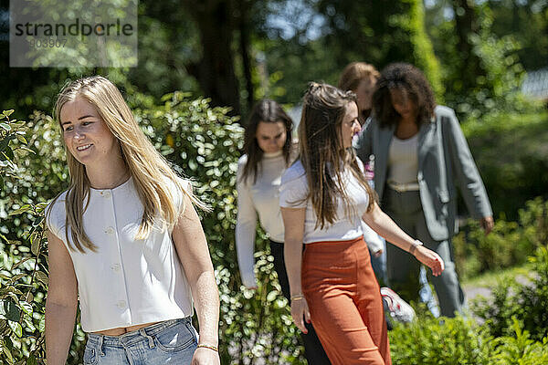 A group of women enjoying a sunny day outdoors  walking and smiling in a garden setting.