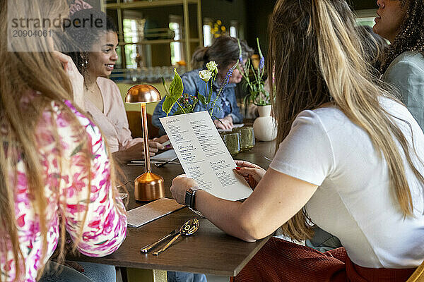 A group of women enjoying a social gathering at a cozy restaurant  with one reading a menu and others engaged in conversation.