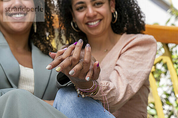 Two women smiling and holding hands  showcasing friendship and connection.