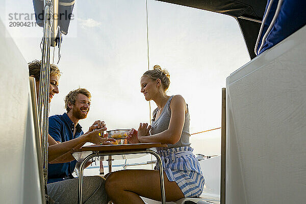 Friends enjoying a meal together on a boat at sunset.