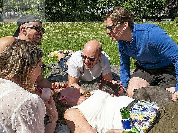 Group of friends enjoying a sunny day at the park with laughter and a picnic.