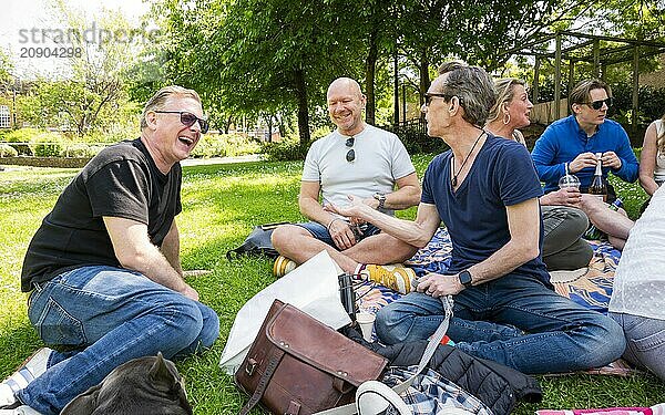 Group of adults enjoying a picnic in a sunny park.