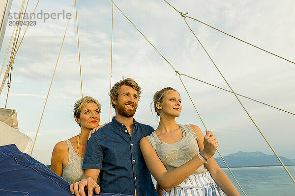 Three people enjoying a serene boat ride at sunset  with a backdrop of a calm sea and a clear sky.